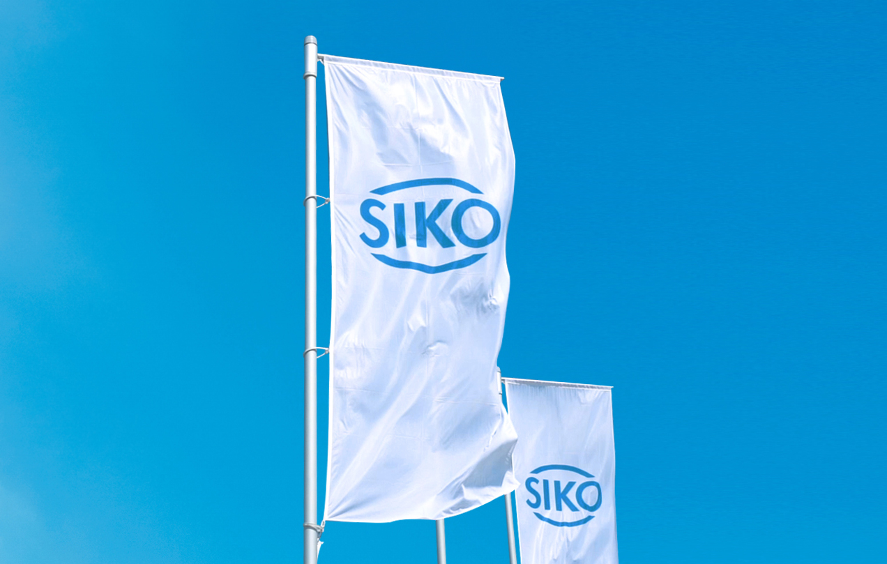 Due bandiere bianche con un logo blu SIKO sventolano al vento